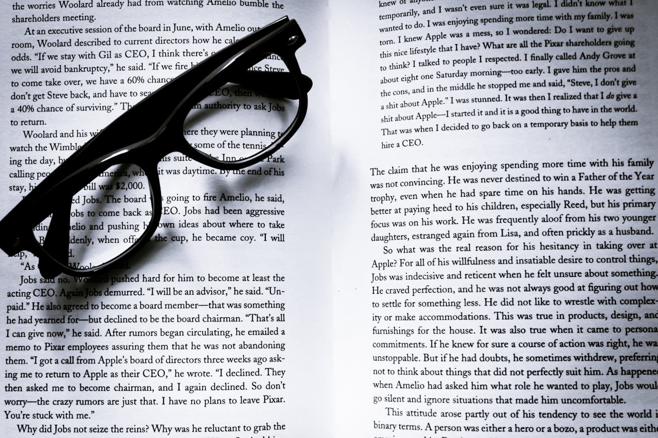 Black eyeglasses on open book pages with visible text, ideal for study themes.